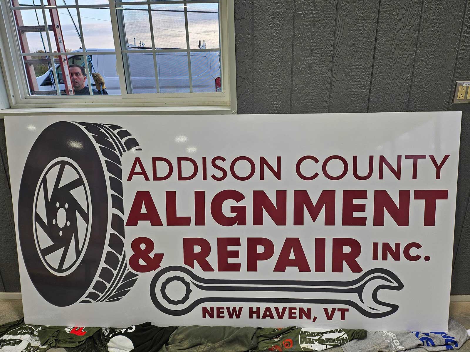 Addison County Alignment and Repair's logo on a banner in their shop in New Haven, VT