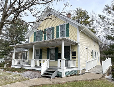 Yellow clapboard house with porch supported by white columns.