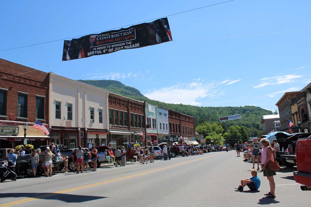 Bristol Main Street store fronts spectators lining sidewalks to view parade on a sunny 4th of July