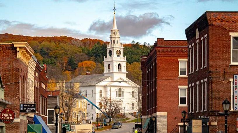 A photo of downtown Middlebury in the fall, looking up toward the church from near the bridge over the falls