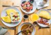 a variety of breakfast dishes on plates on a table as seen from above