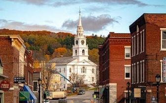 A photo of downtown Middlebury in the fall, looking up toward the church from near the bridge over the falls