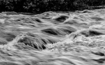 a black and white image of a rushing river